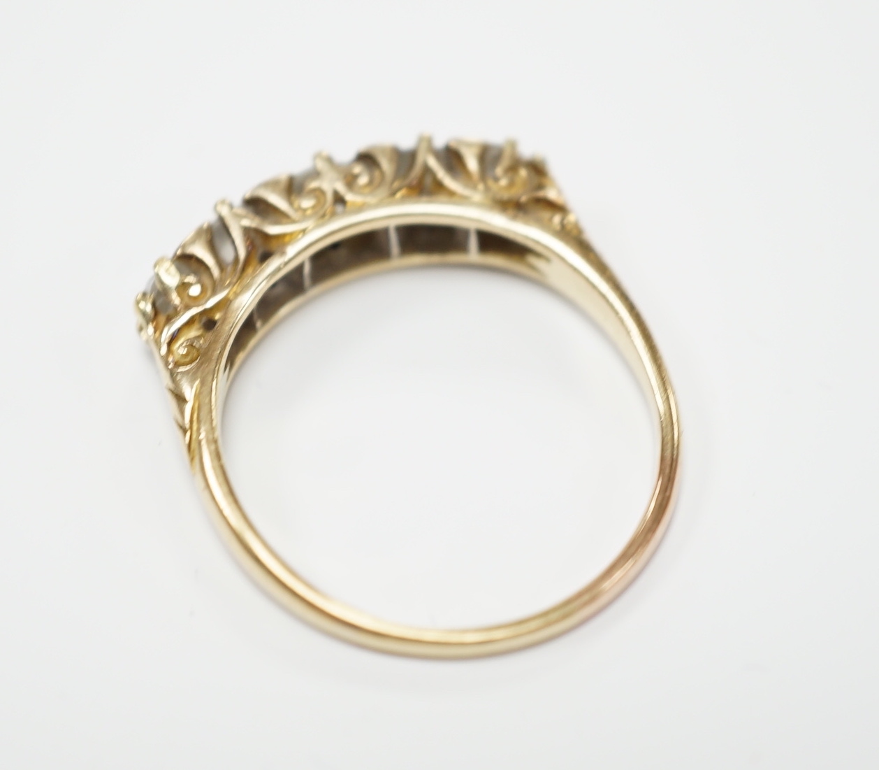 A yellow metal and graduated five stone diamond set half hoop ring, size Q, gross weight 3.9 grams.